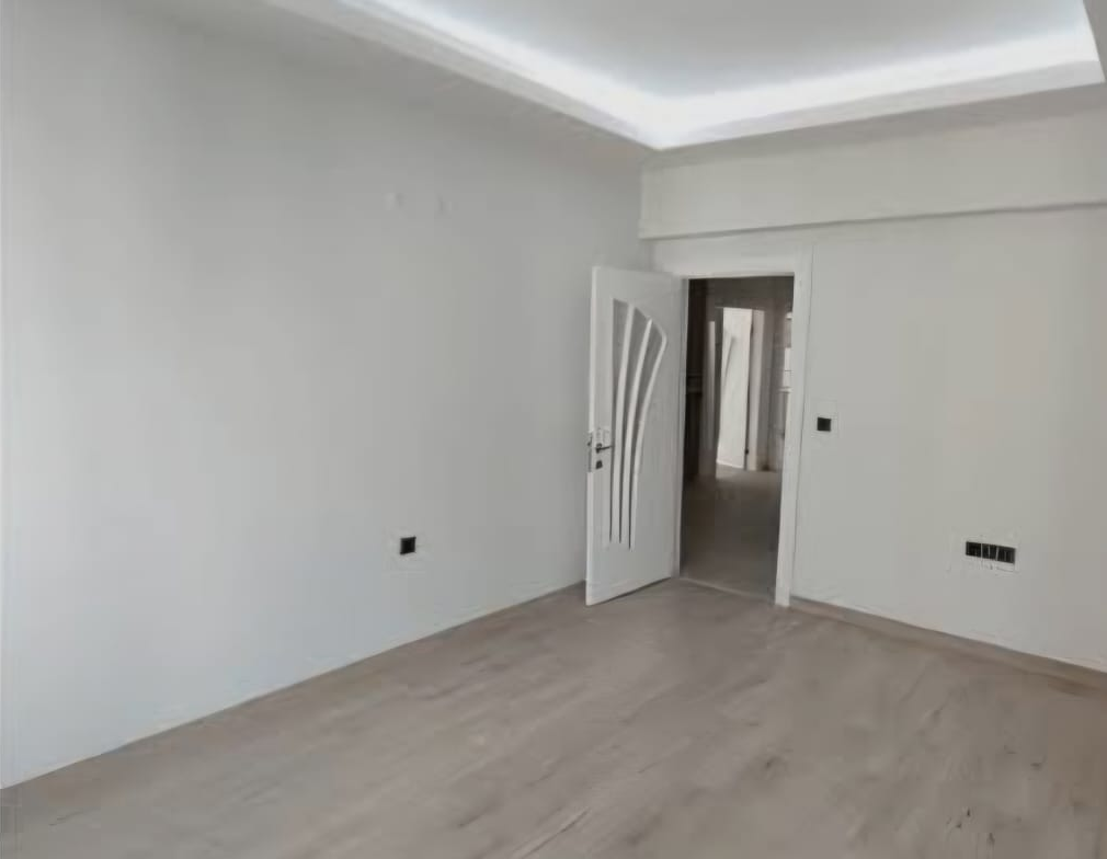 Kırmızı duvarları açık renge boyanıp zemini yenilenmiş oda